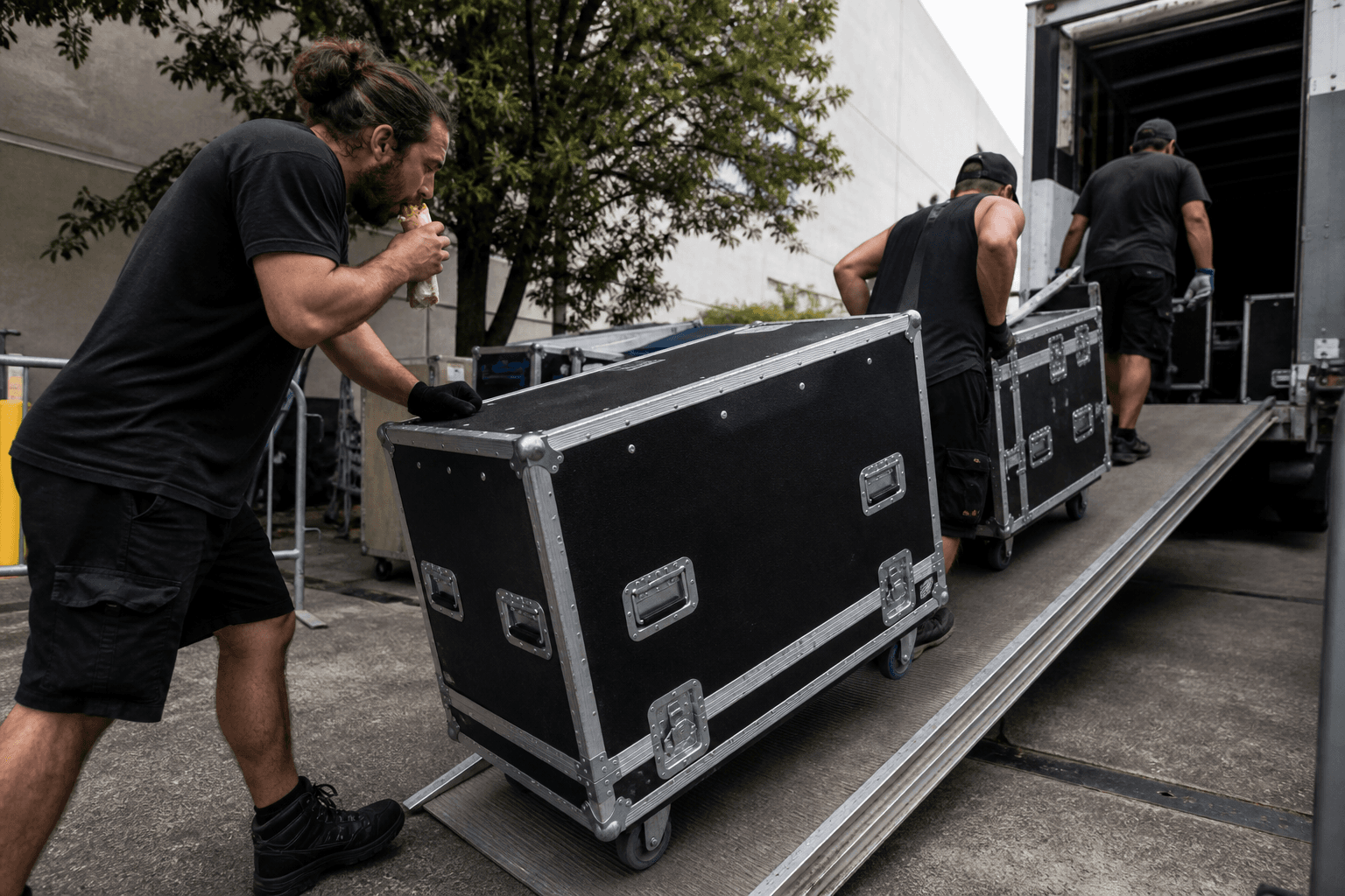 Roadies rolling flight cases up a venue ramp at load-in