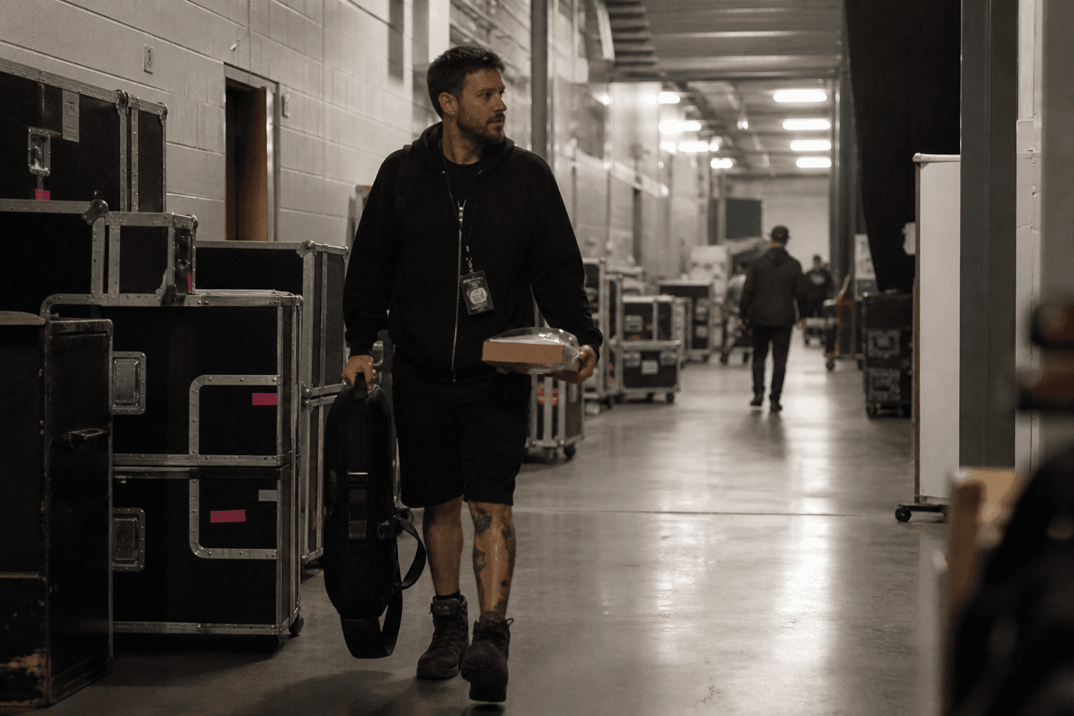 Roadie walking a backstage hallway with a gig bag and meal